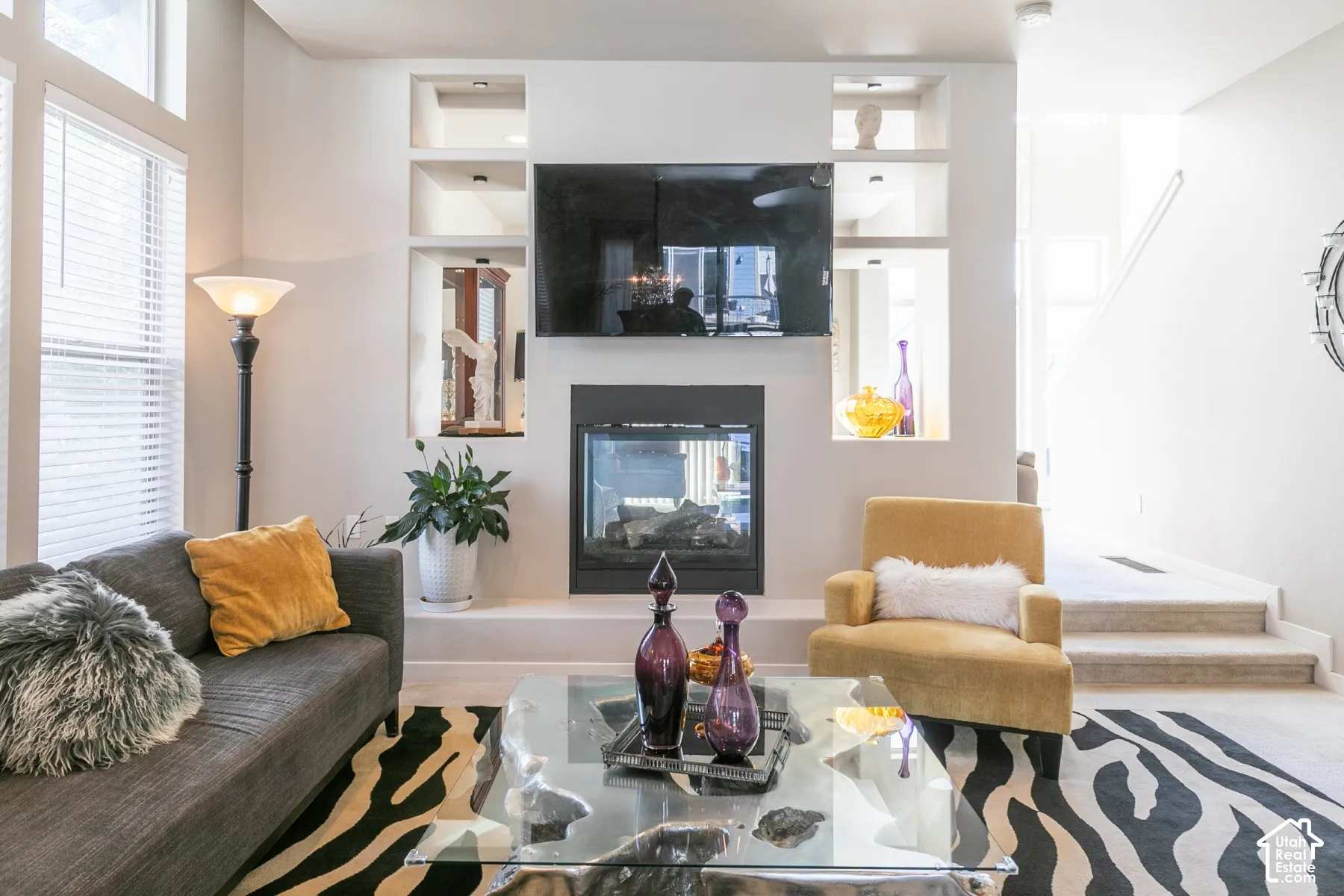 Recessed wall niches with accent lighting, built-in fireplace, and large windows with blinds