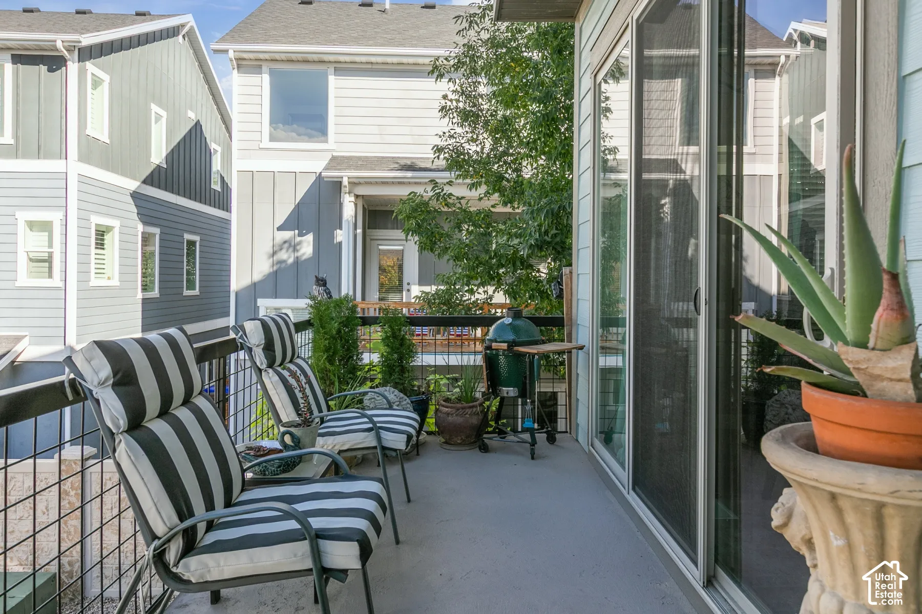 Paved outdoor balcony featuring a metal railing and sliding glass door access