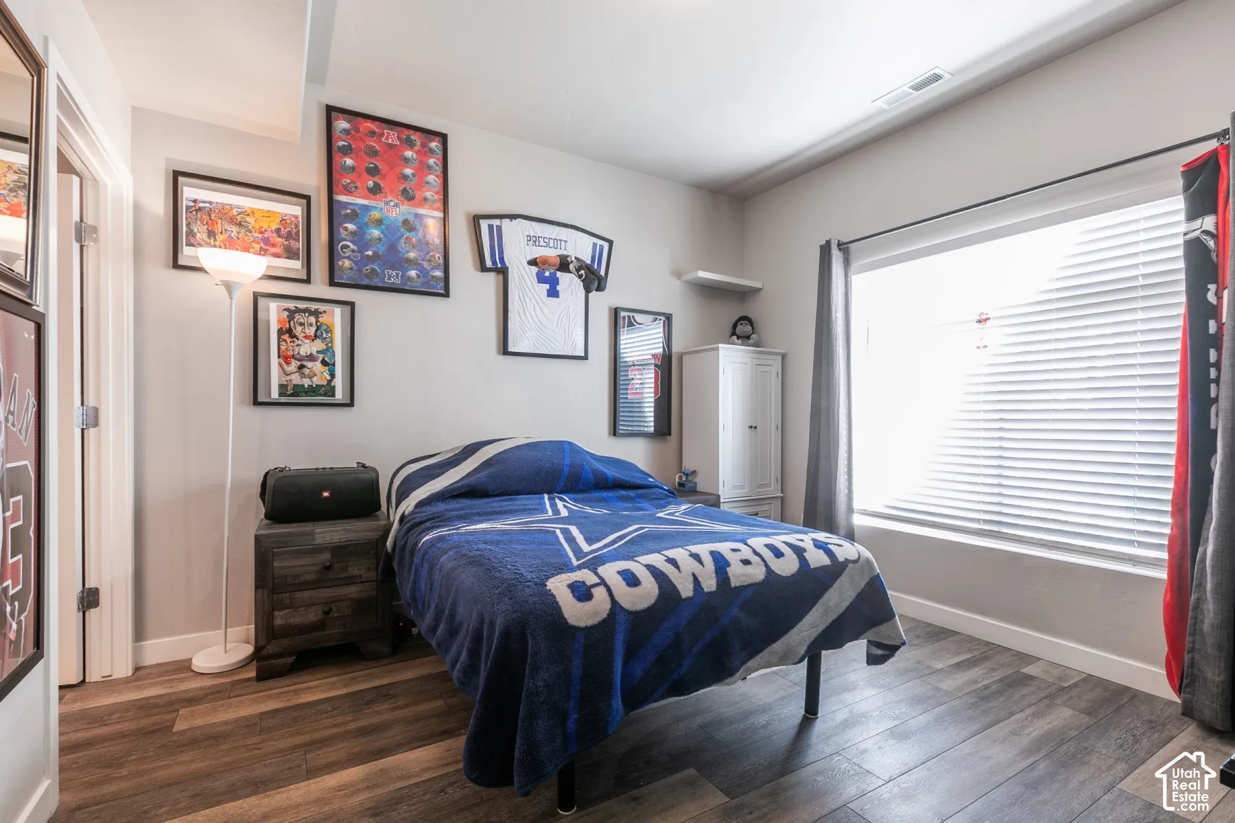 Wood-finish flooring, a large window with blinds, and white trim