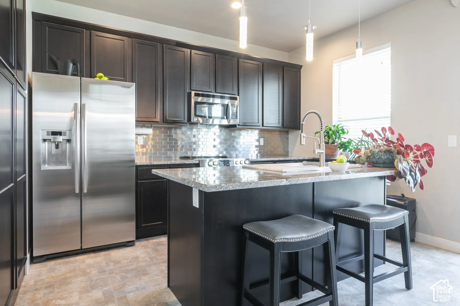 Dark wood cabinetry with stainless steel appliances, granite countertops, and a tiled backsplash