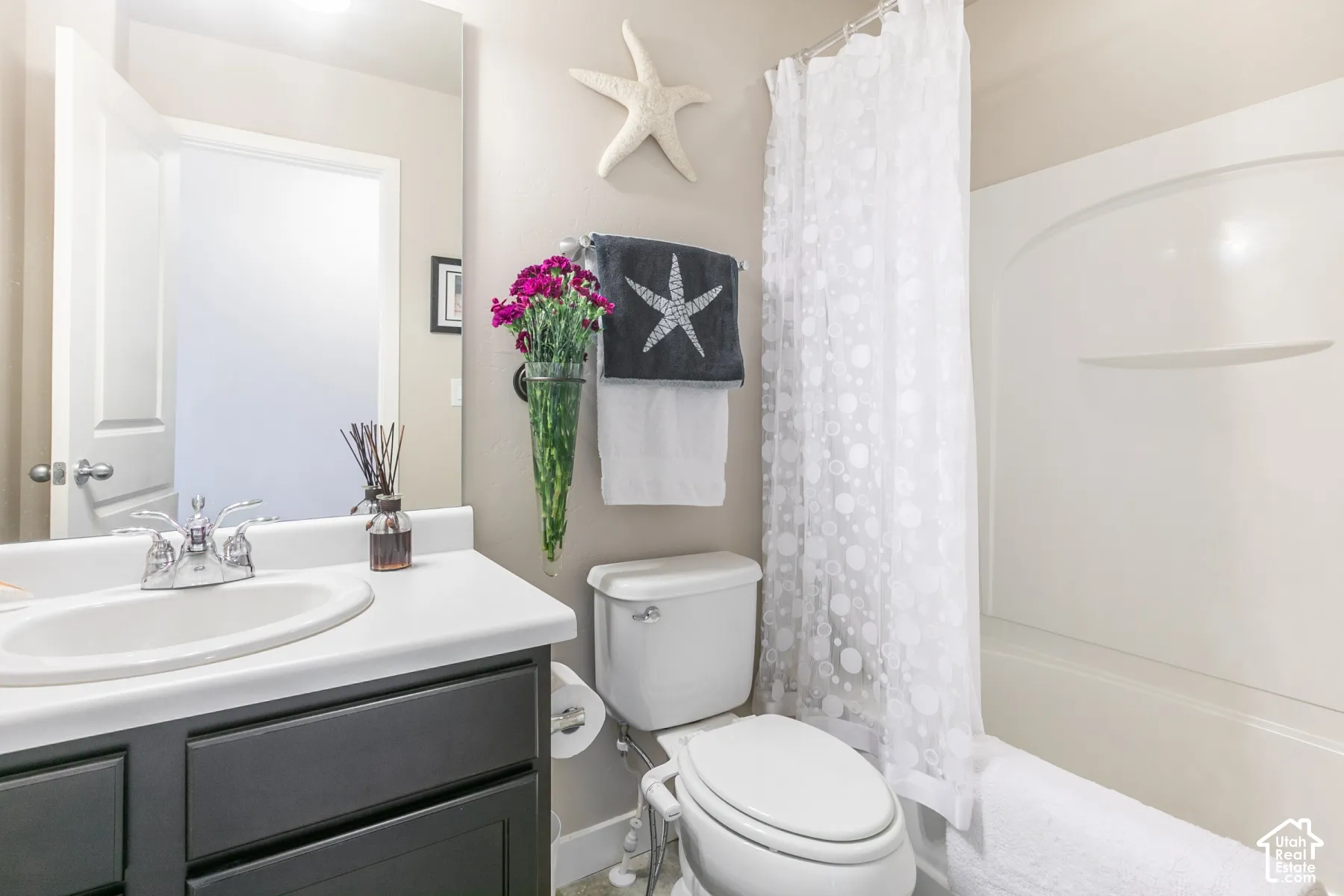 Bathroom featuring a single-basin vanity with a dark gray cabinet, white countertop, and chrome faucet