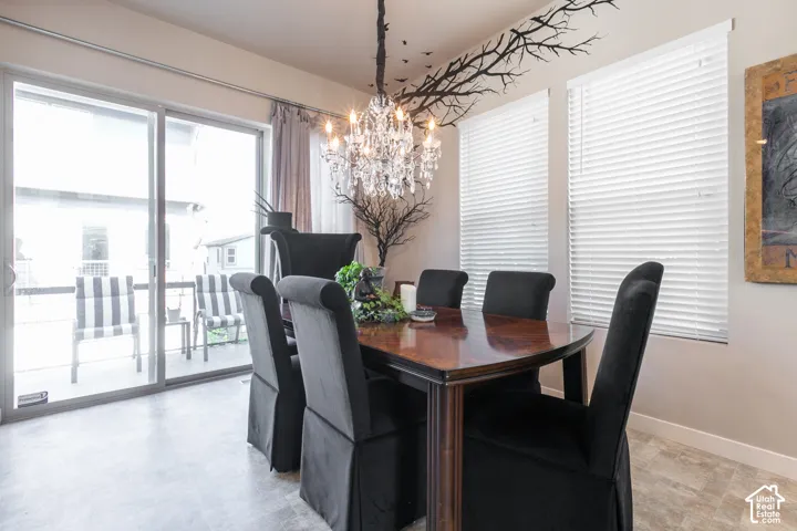 Sliding glass patio door with an adjacent window, a crystal chandelier, and tile flooring
