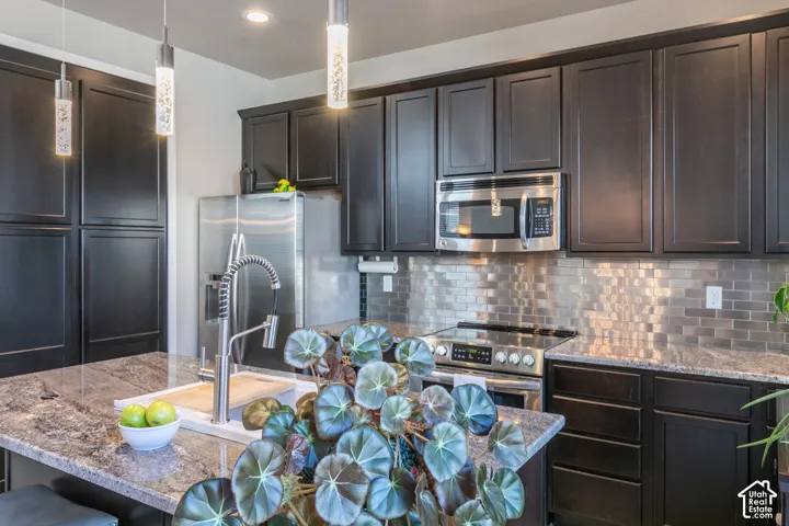 Dark cabinetry with integrated stainless steel appliances and a tile backsplash