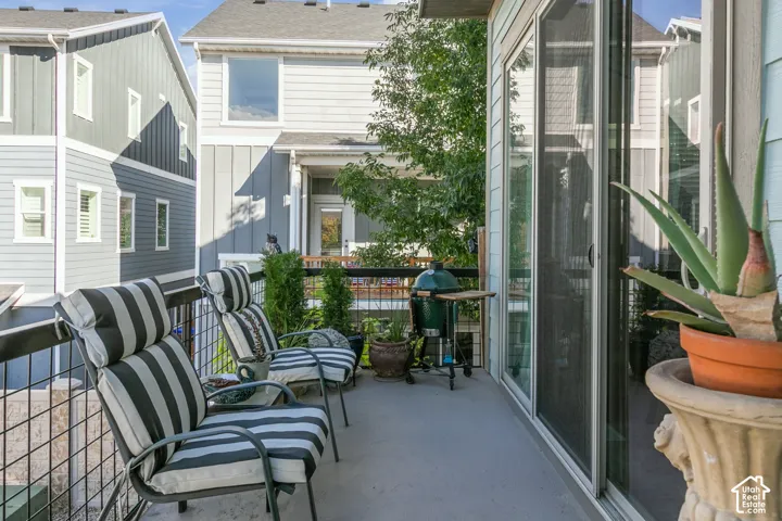 Paved outdoor balcony featuring a metal railing and sliding glass door access