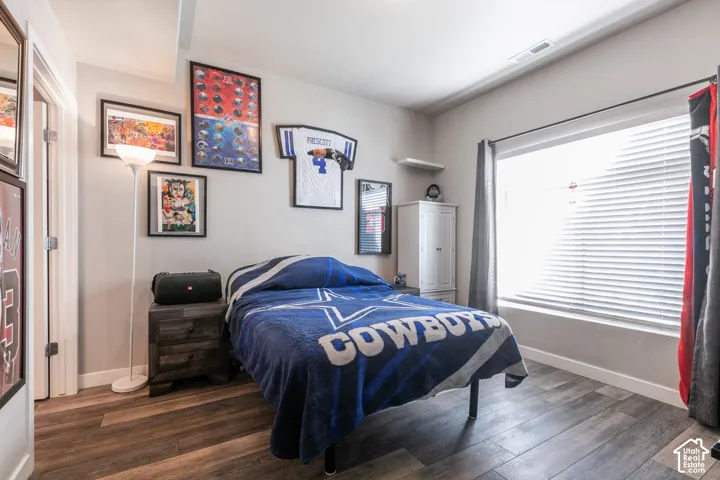 Wood-finish flooring, a large window with blinds, and white trim