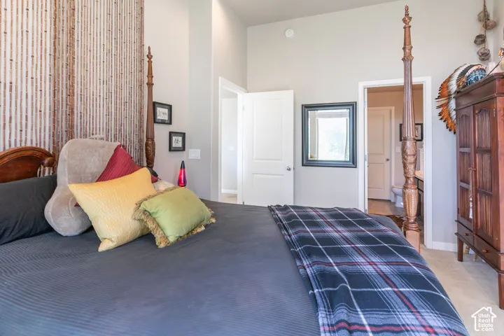 Vaulted ceiling, interior doors, wall-mounted mirror, light-toned carpeting, and wood-finish cabinetry