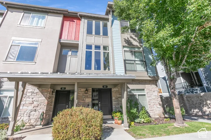 Modern multi-story exterior featuring a mix of stucco, siding, and stone cladding
