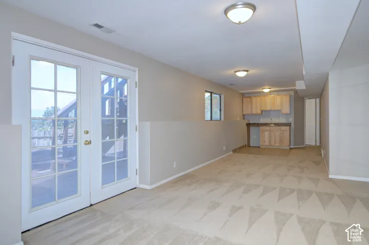 Double French doors, built-in wet bar with wood cabinetry, integrated sink, and recessed lighting, patterned carpet flooring, and two windows