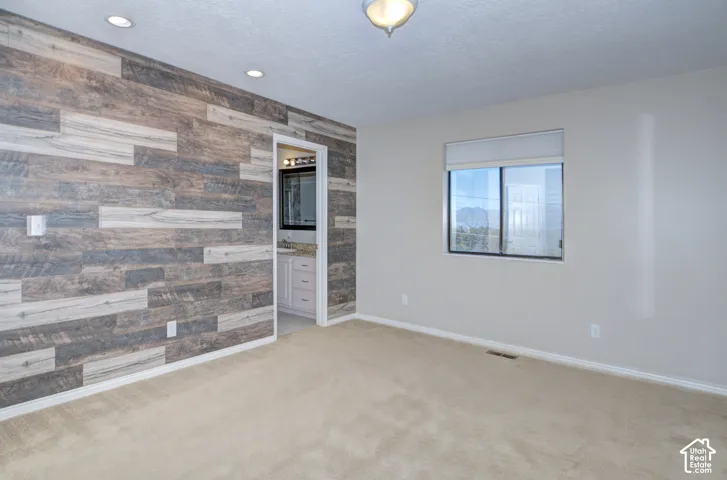 Accent wall with wood-finish paneling, recessed lighting, and neutral carpet flooring