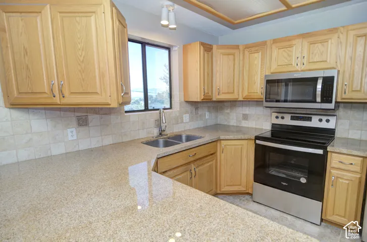 Kitchen featuring wood cabinetry, stone-finish countertops, stainless steel appliances, and a tile backsplash