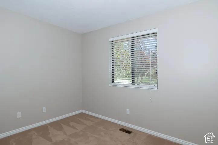 Bright corner bedroom with expansive window featuring plantation shutters, allowing abundant natural light