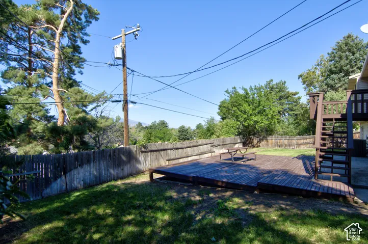 Spacious backyard retreat featuring a composite deck with integrated seating, mature landscaping with established trees, wooden privacy fencing, and level lawn space ideal for outdoor entertaining