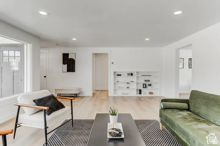 Recessed ceiling lighting, wood-finish flooring, built-in shelving, and white interior paint