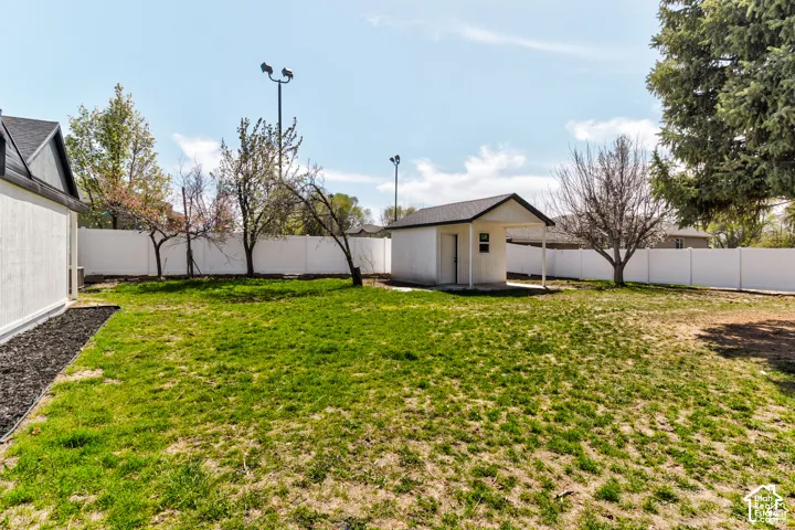 Expansive backyard with a manicured lawn, white privacy fencing, and a detached outbuilding with a covered porch