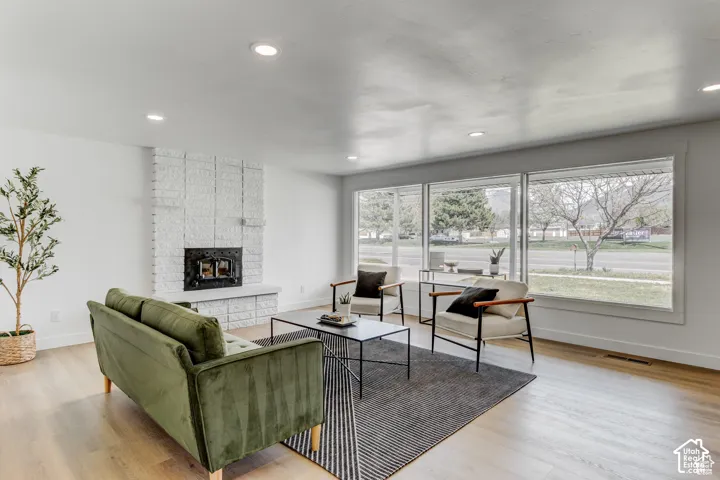 Recessed lighting, wood-finish flooring, white brick fireplace, and large windows