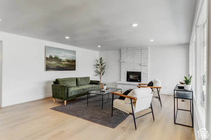 Wood-finish flooring, recessed lighting, white brick fireplace, and tall windows