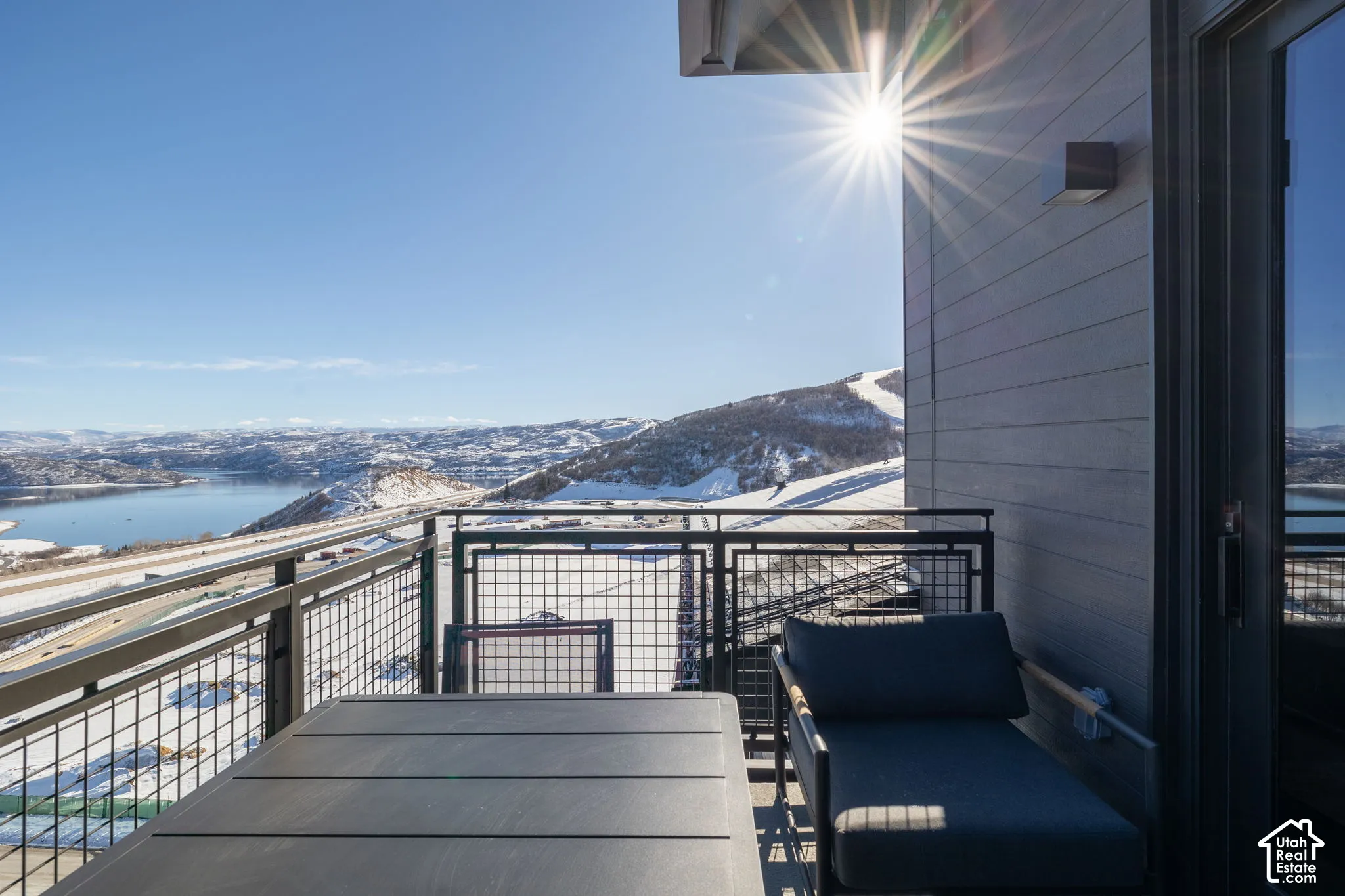 Exterior balcony with metal railing, water body, and distant snow-covered mountains