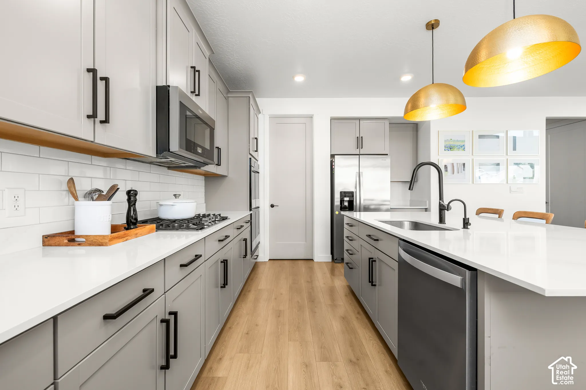 Kitchen featuring a gas range, stainless steel appliances, light wood-finish flooring, and a large island with sink and integrated dishwasher