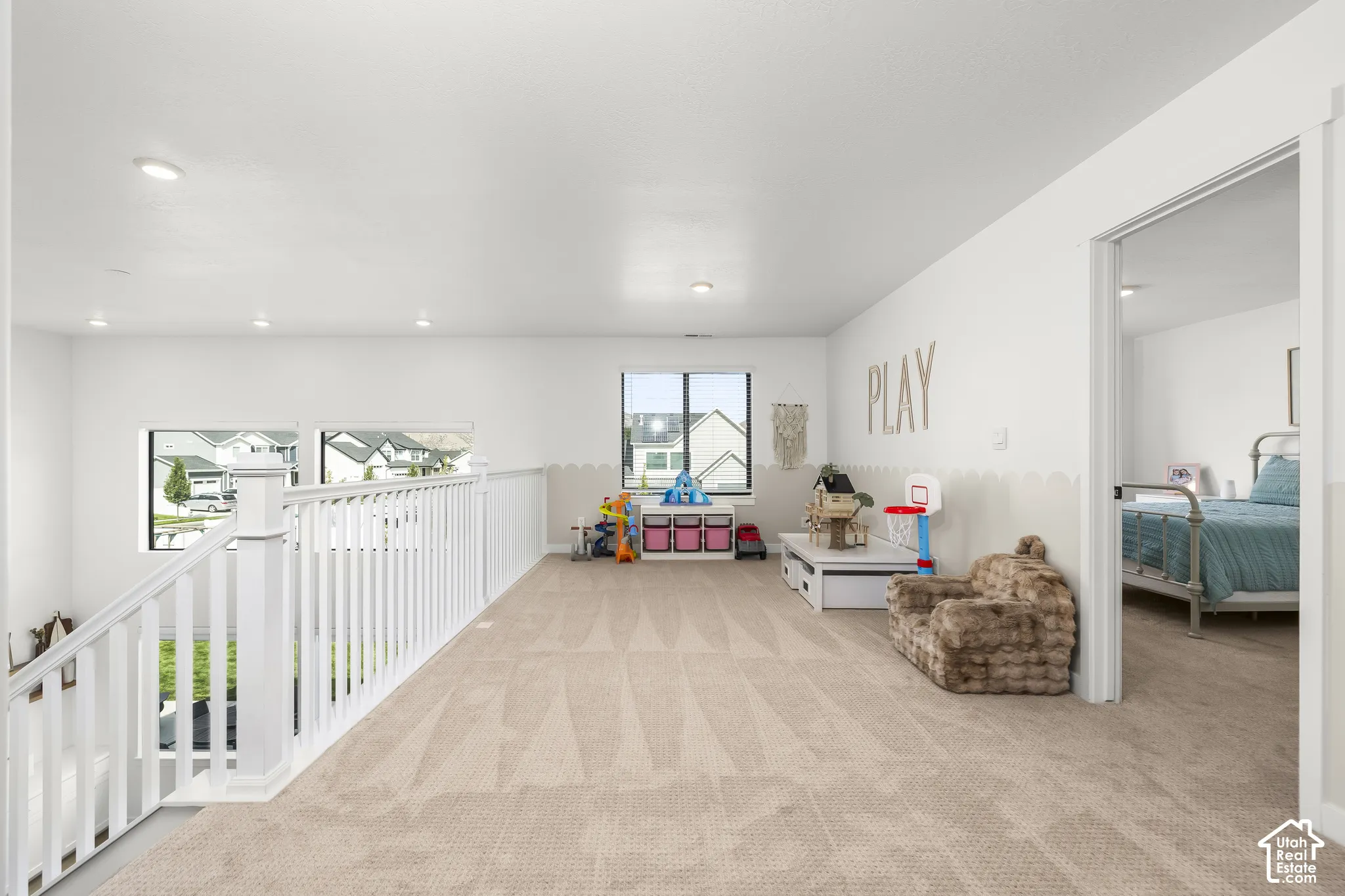 Bright, open loft space with carpeted flooring, recessed lighting, and white railings