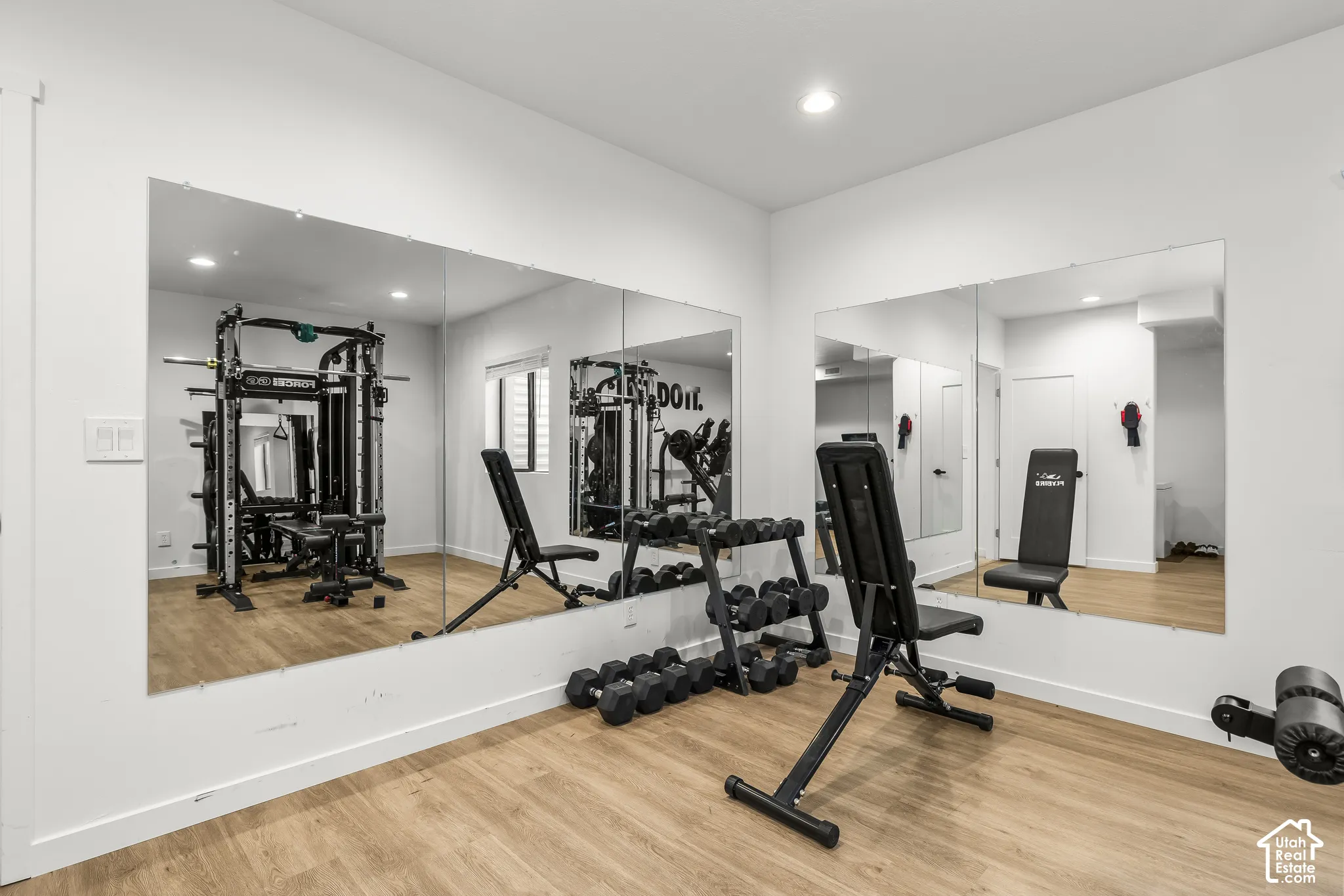 Dedicated fitness area featuring expansive wall-mounted mirrors and wood-finish flooring