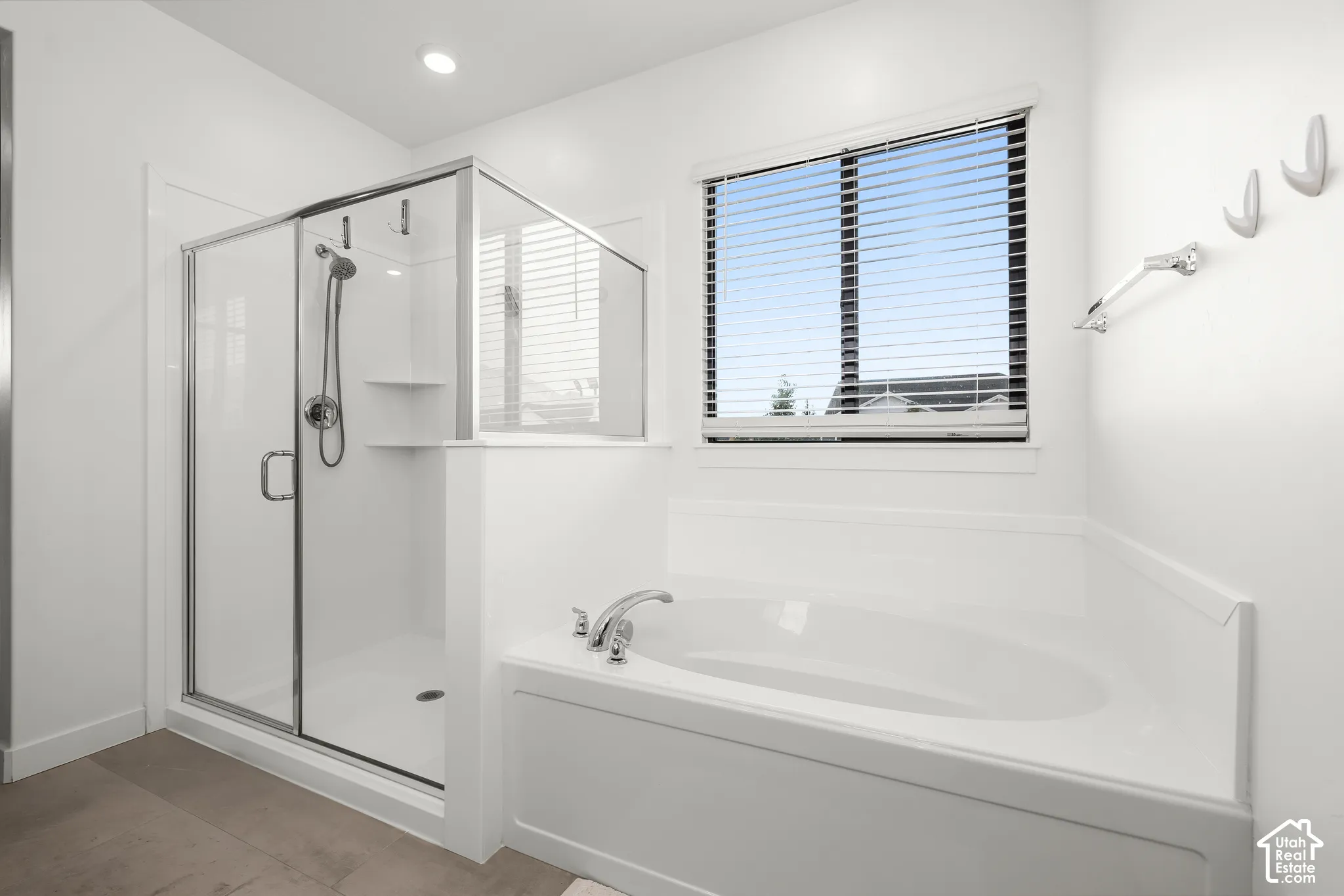 Soaking tub with chrome fixtures, glass-enclosed shower, window with blinds, recessed lighting, and tile flooring