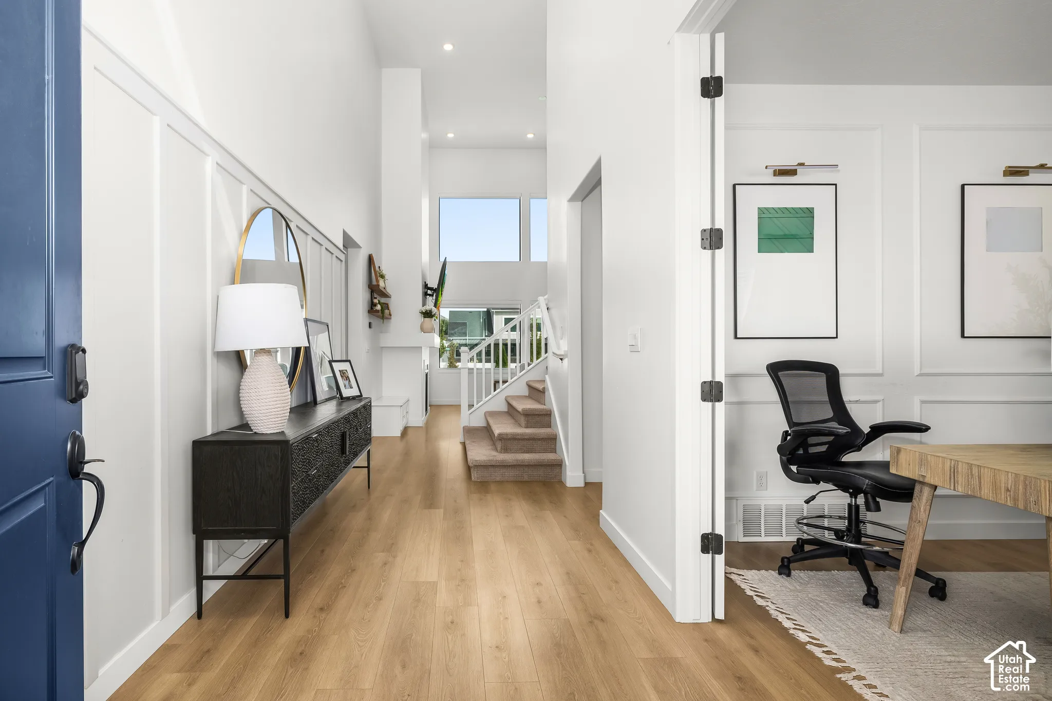 Two-story entry with wood-finish flooring, white board and batten wall detailing, and a contemporary staircase with carpeting