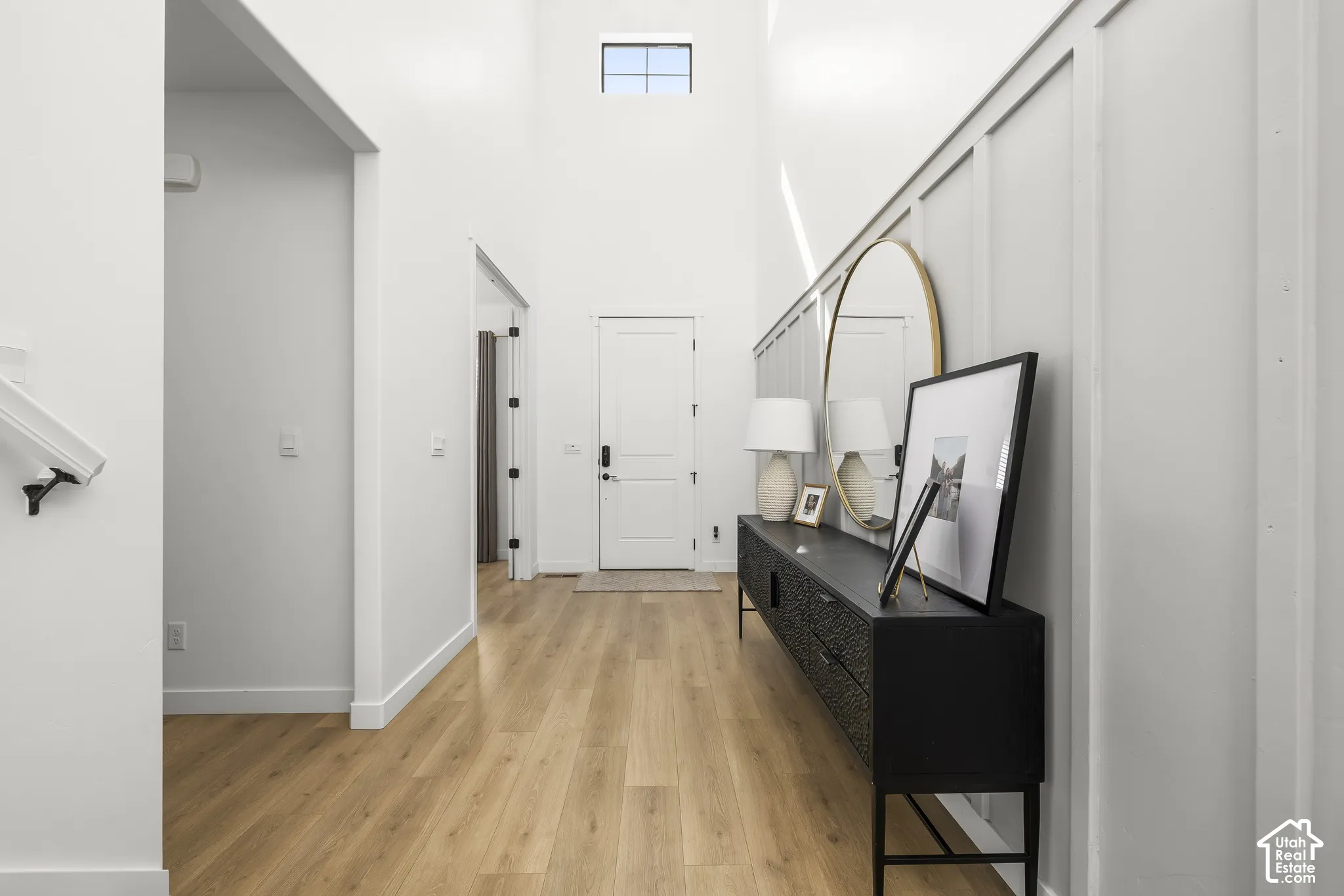 Two-story entryway with wood-finish flooring, white walls, and a transom window