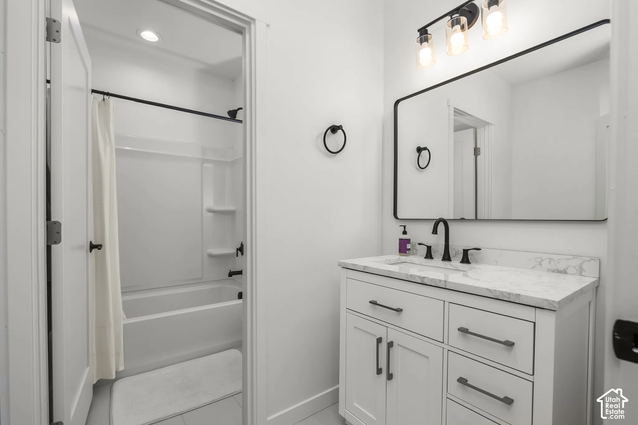 Vanity with a light-toned countertop, under-mount sink, matte black faucet, and white cabinetry