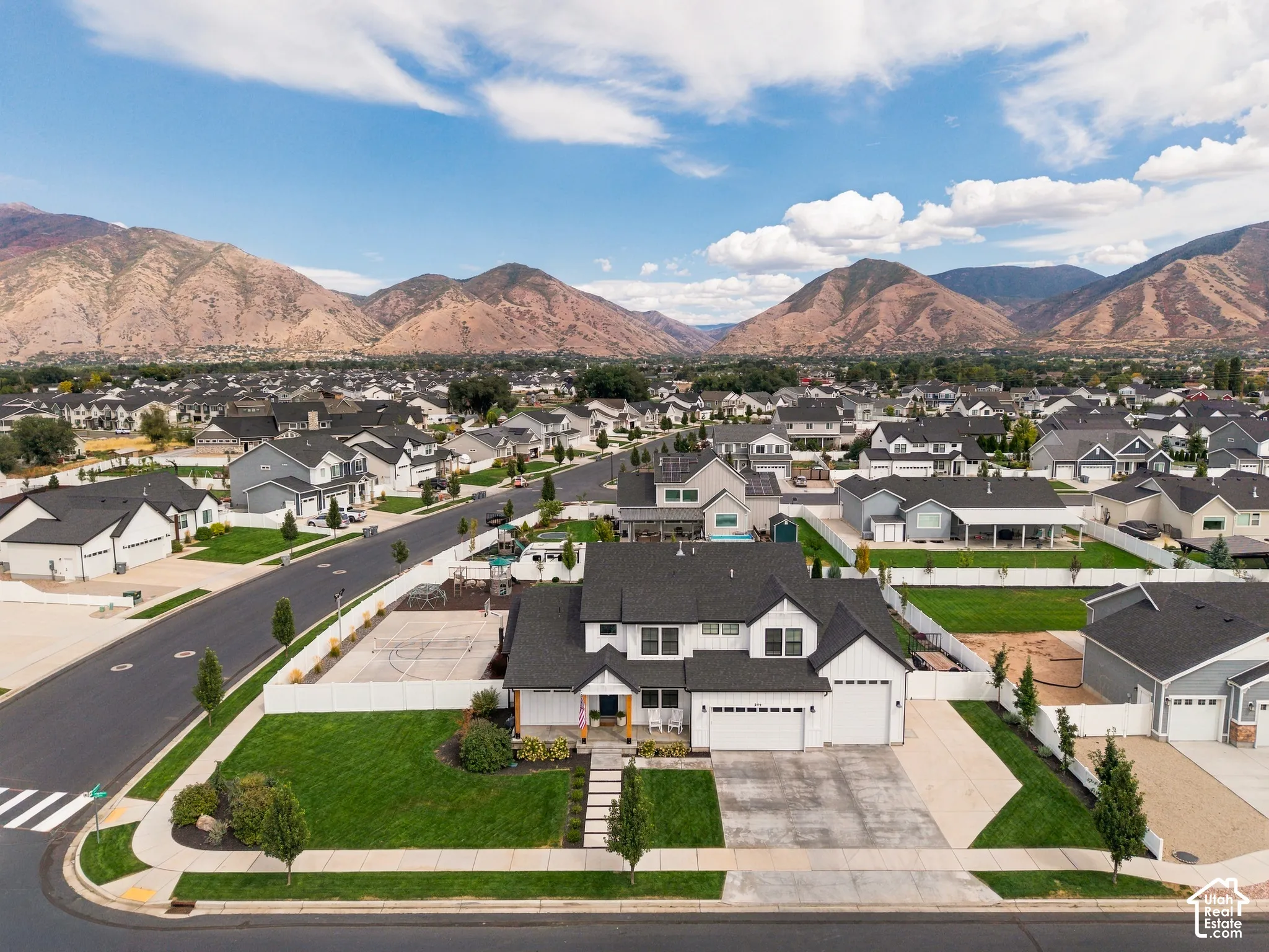 Modern farmhouse-style residence with a two-car garage, white fencing, and a manicured lawn
