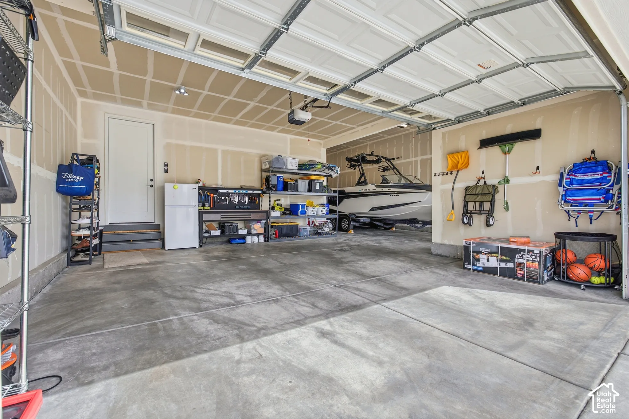 Spacious garage with multiple bays, exposed ceiling joists, interior access door, and painted drywall