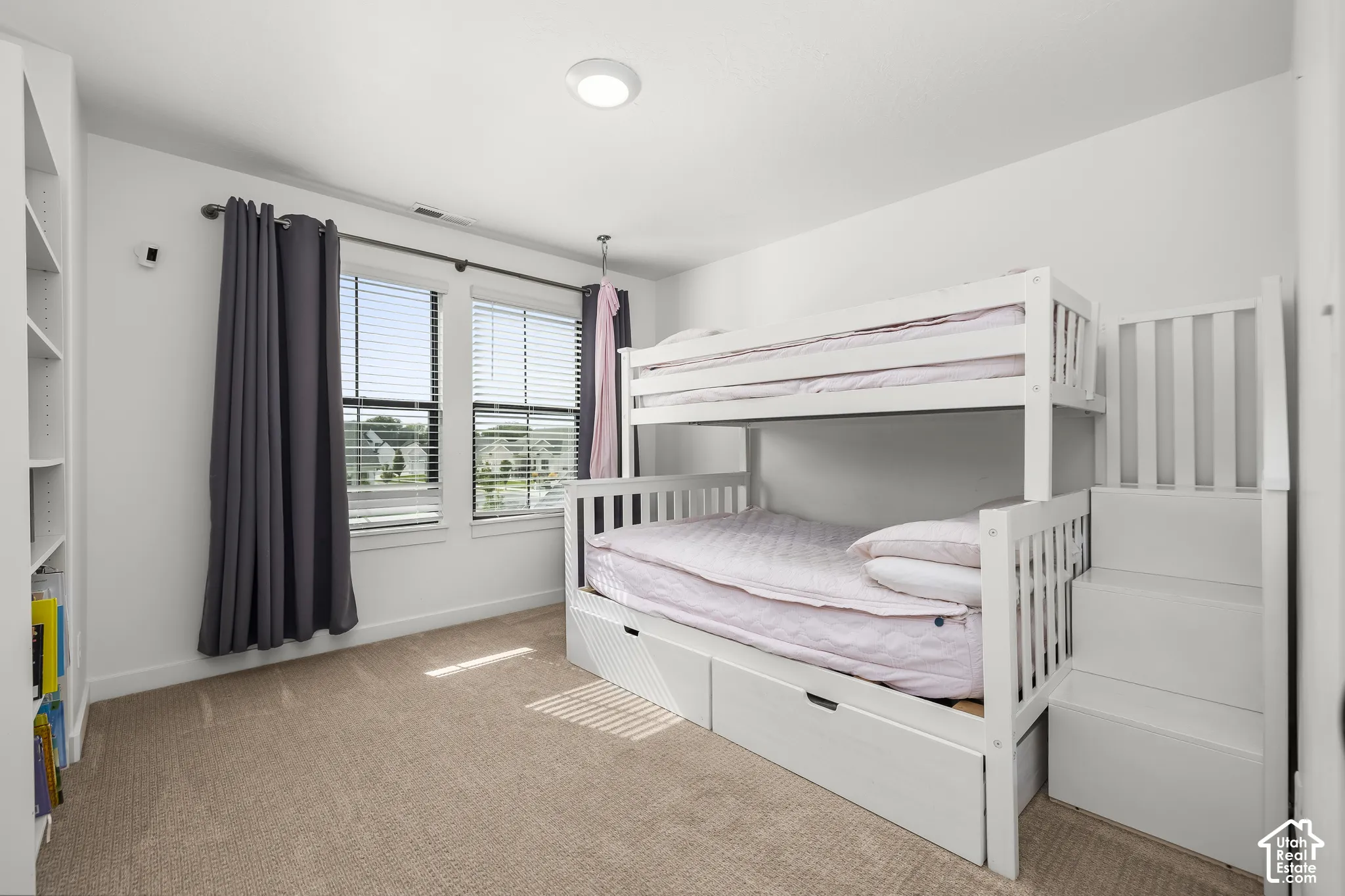 Recessed ceiling light, built-in shelving, dual windows with blinds, and neutral-toned carpeting