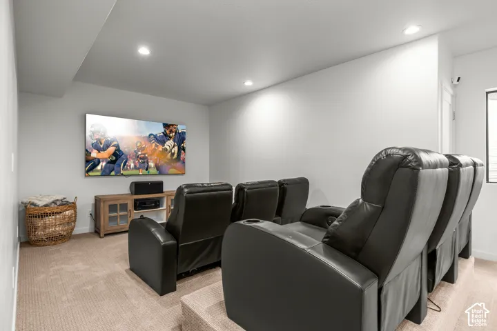 Entertainment room featuring a large wall-mounted screen, recessed lighting, and carpeting