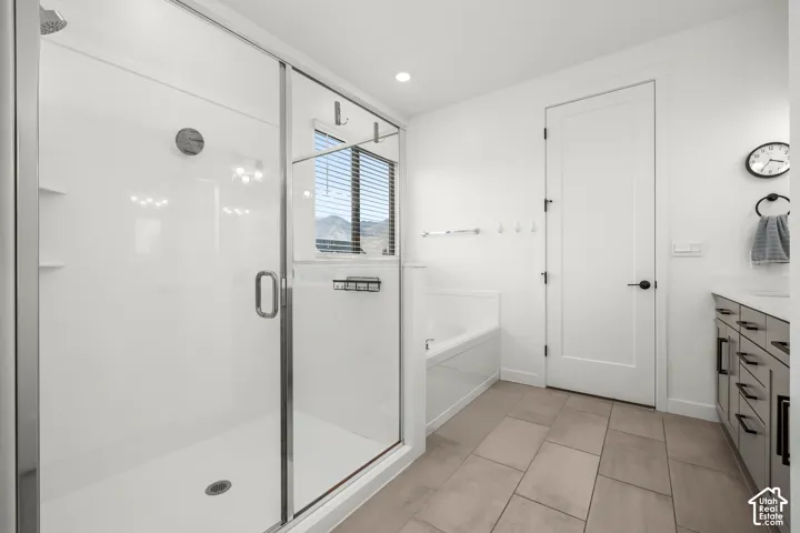 Glass-enclosed shower with a rainfall showerhead, separate soaking tub, and a vanity with an undermount sink