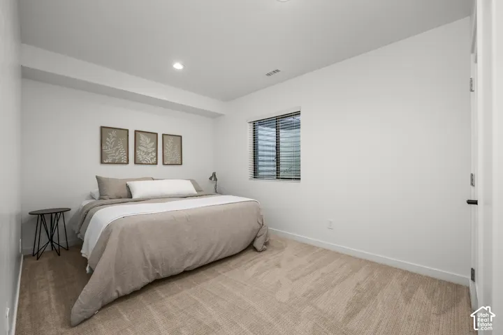 Recessed lighting, light-colored carpeting, white interior walls, and a window with blinds