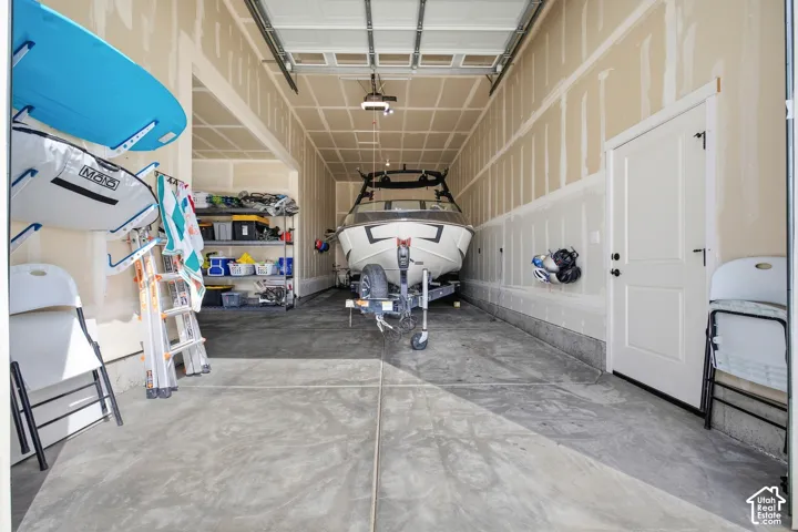 Spacious garage with exposed framing, concrete flooring, and an interior access door