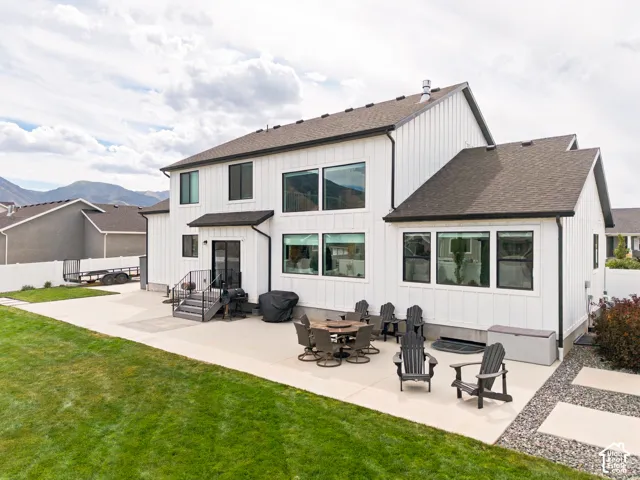 Expansive concrete patio with integrated gravel pathways, large windows, dark-framed sliding glass door, and white vertical siding