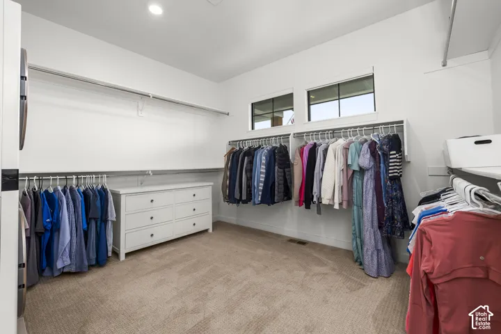 Spacious walk-in closet featuring recessed lighting, high ceilings, built-in shelving, a six-drawer dresser, and carpet flooring
