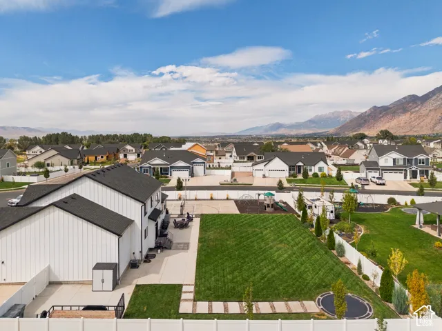 Expansive backyard featuring a manicured lawn, paved patio, and white privacy fencing