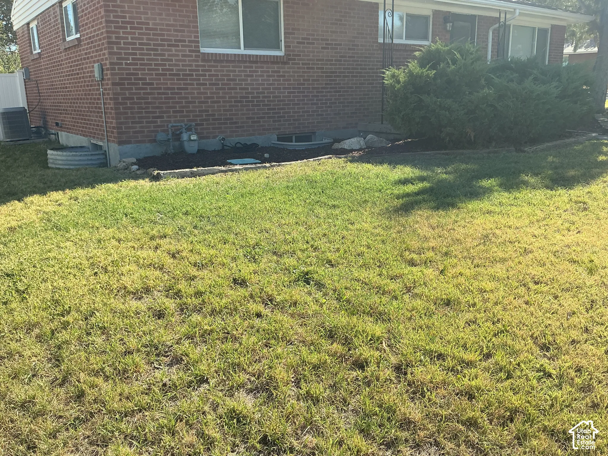 Red brick exterior, ground-level windows, mature landscaping, manicured lawn