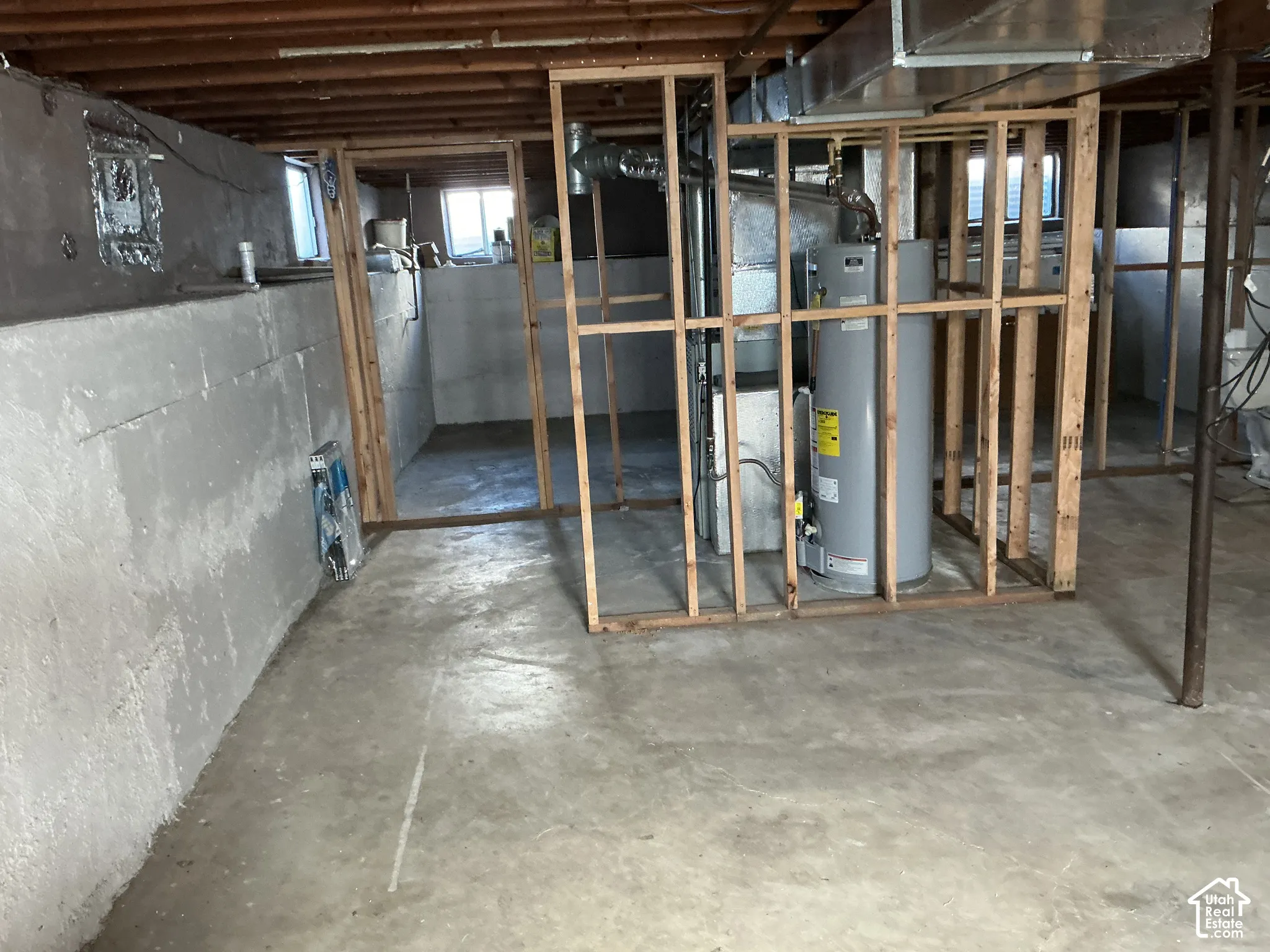 Unfinished basement with exposed ceiling joists, concrete floor, framed interior walls, and visible utility systems