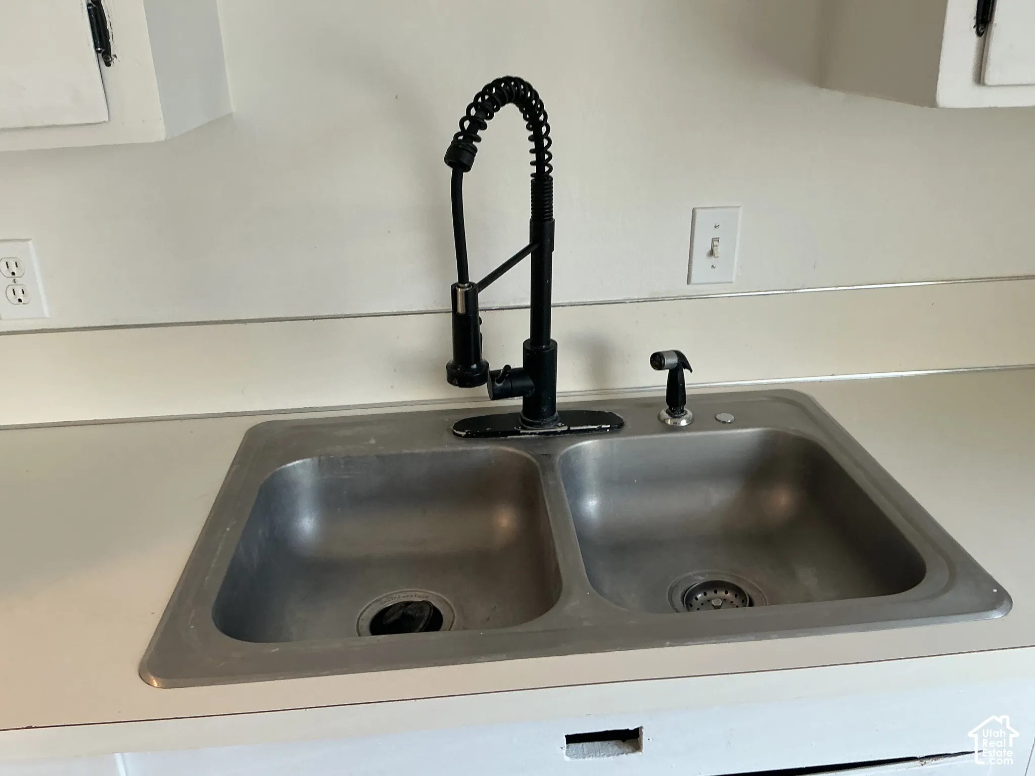 Double basin stainless steel sink with a matte black pull-down faucet and matching side sprayer
