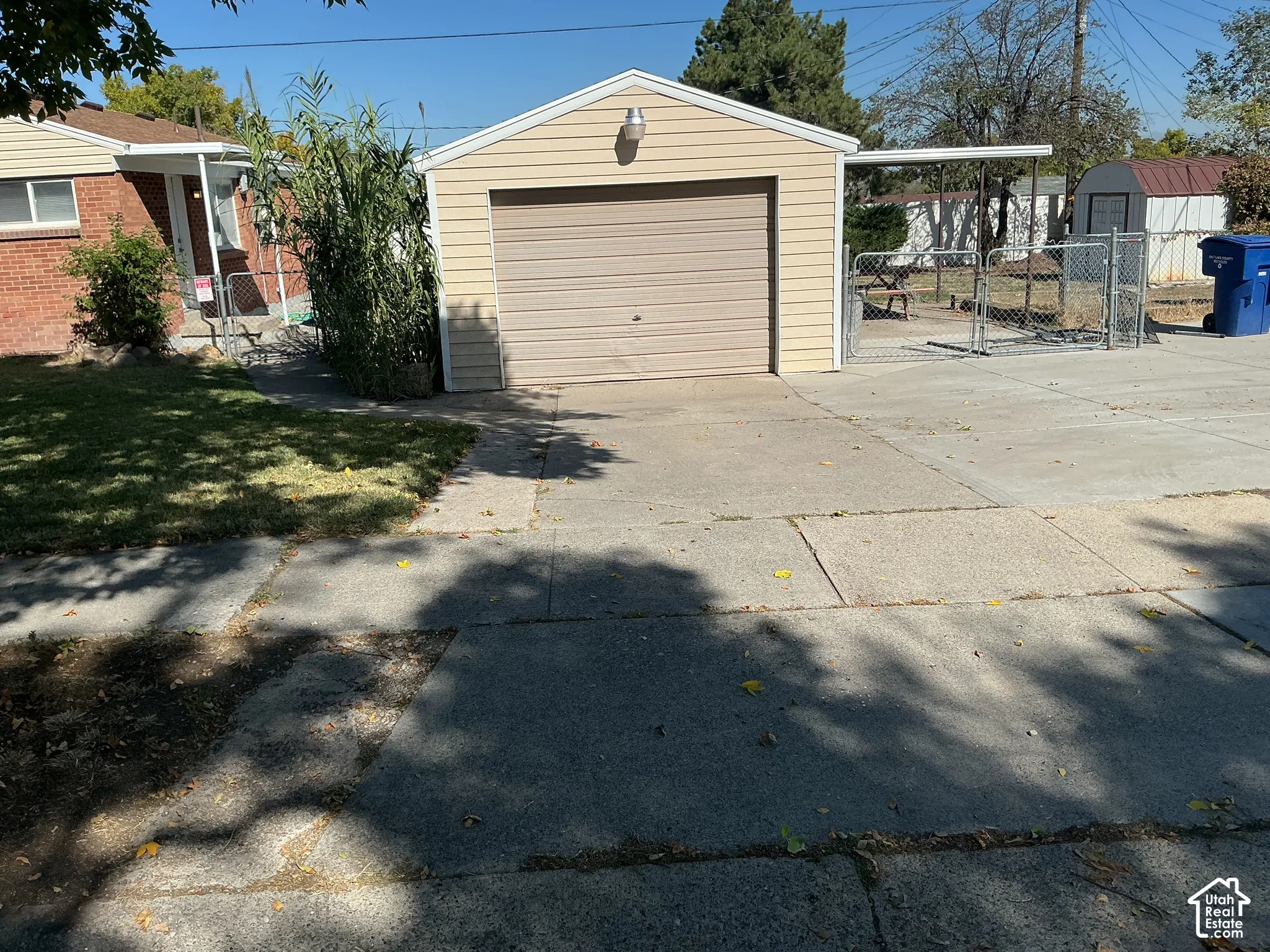 Detached garage with horizontal siding and an overhead door, concrete driveway, and chain-link fencing