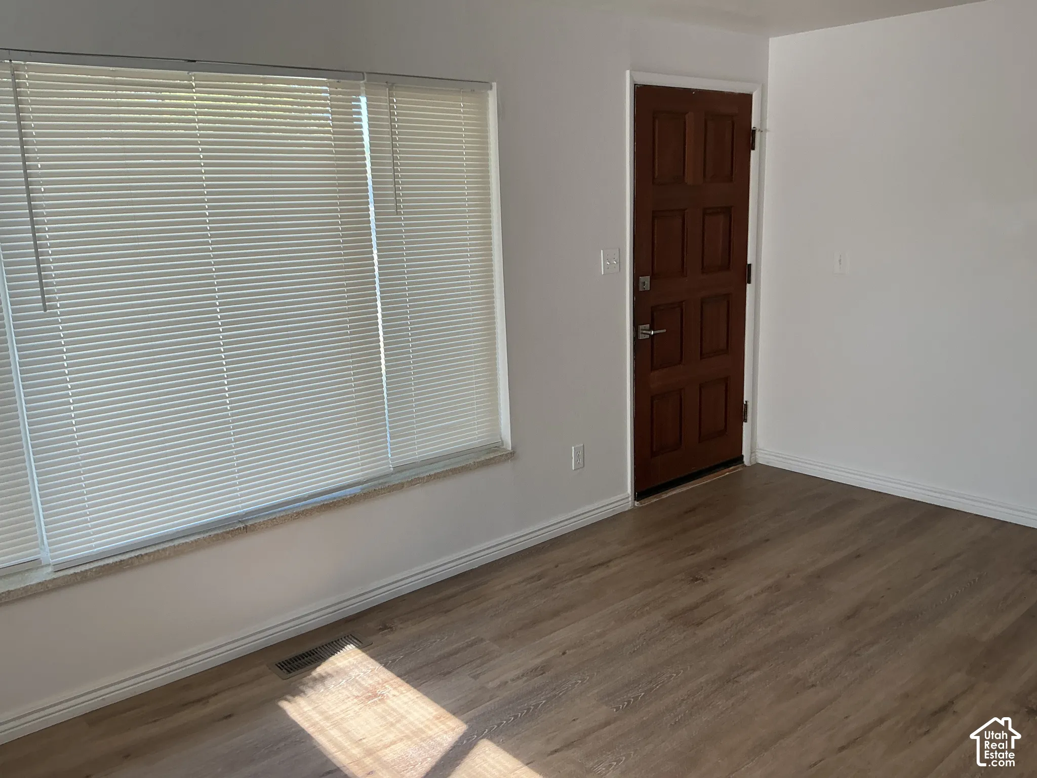 Wood-finish flooring, white painted walls, and a multi-paneled wood entry door