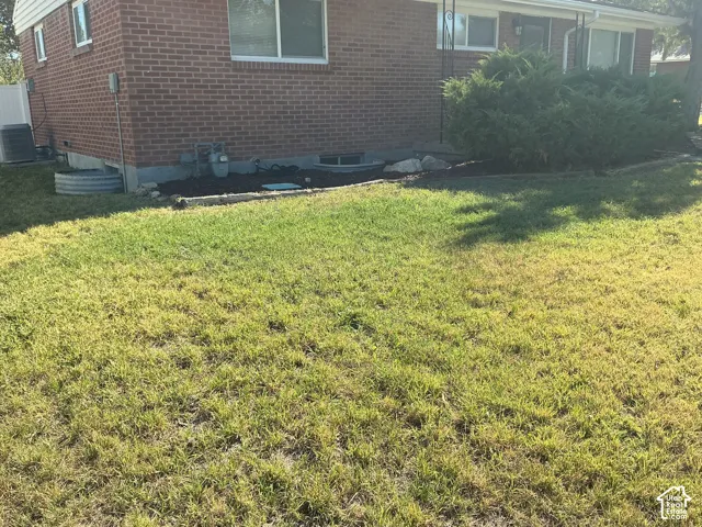 Red brick exterior, ground-level windows, mature landscaping, manicured lawn