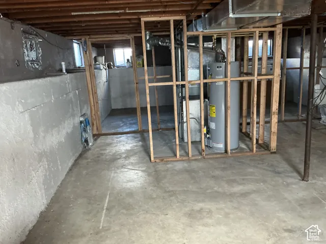Unfinished basement with exposed ceiling joists, concrete floor, framed interior walls, and visible utility systems