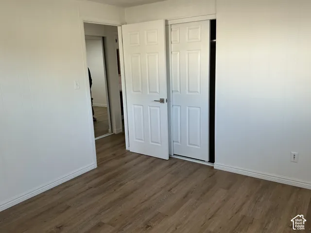 Wood-finish flooring with white baseboards, white paneled walls, and white paneled doors