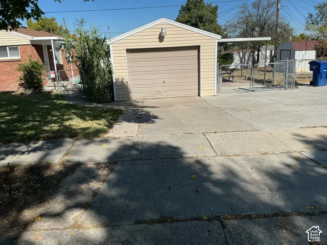 Detached garage with horizontal siding and an overhead door, concrete driveway, and chain-link fencing
