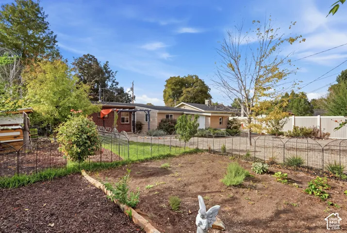 Spacious outdoor area featuring a planted garden bed, wrought iron fencing, and mature landscaping
