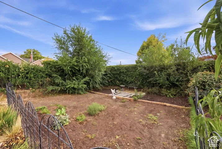 Fenced rear yard with established perimeter hedging and mature trees