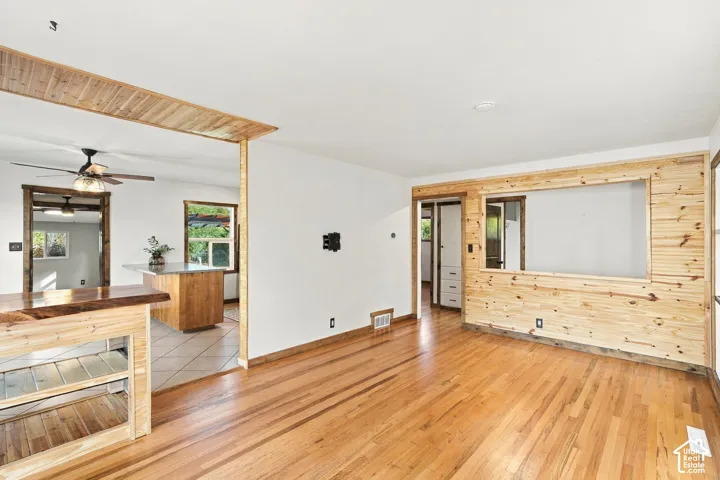 Hardwood flooring, wood-paneled accent wall, wood-finish room divider, built-in shelving, and recessed lighting